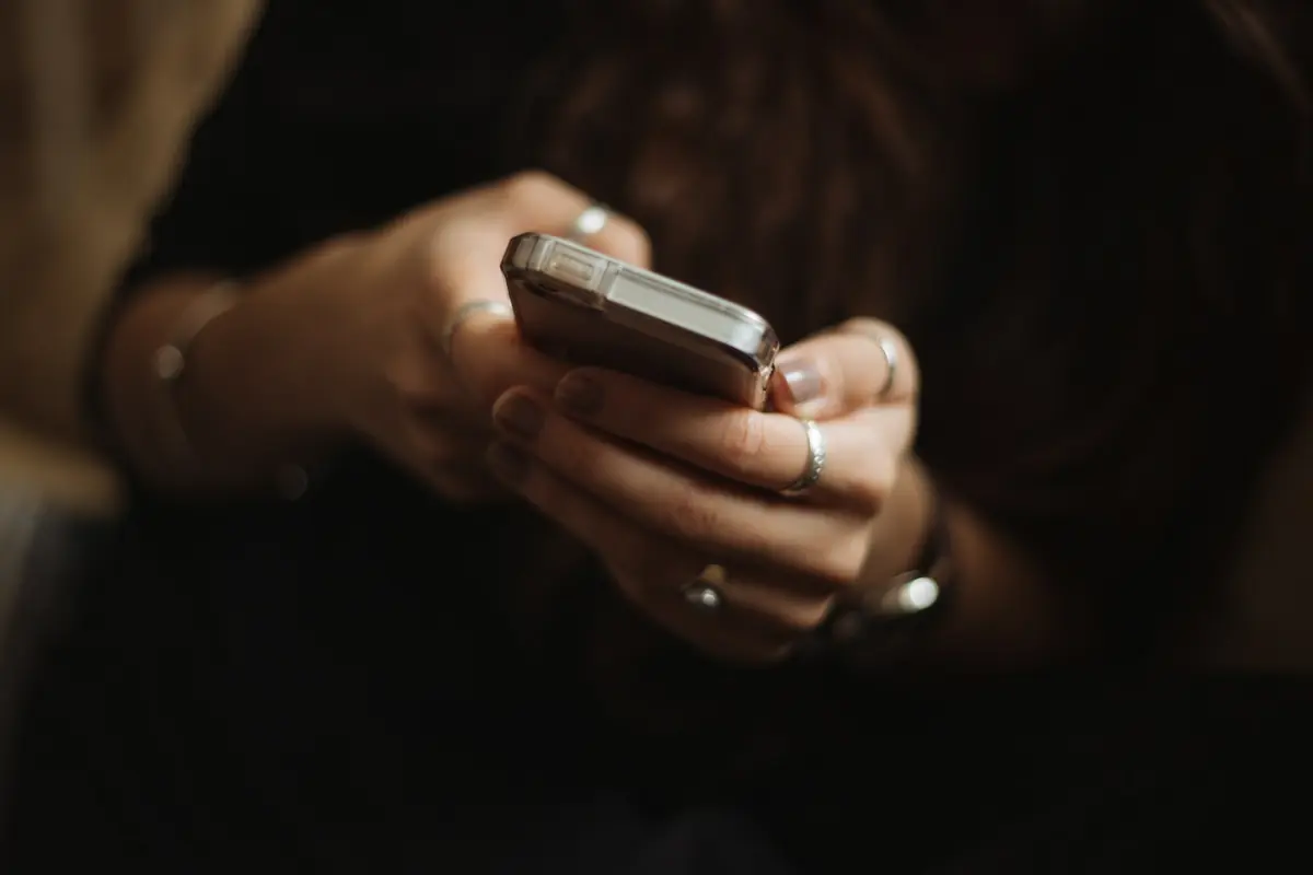 Pessoa rola a tela do celular em um ambiente escuro.